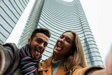 Tourist couple making phone camera selfie with city skyscraper in background
