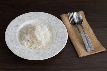 White Rice in the dish on dark brown wooden plate