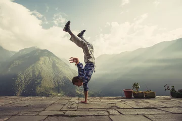 Foto op Canvas Young sporty man doing handstand exercise in beautiful mountain landscape. Sports outdoor lifestyle © Annatamila