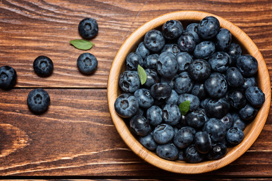 Fresh blueberries in the bowl on a wooden table. Top view