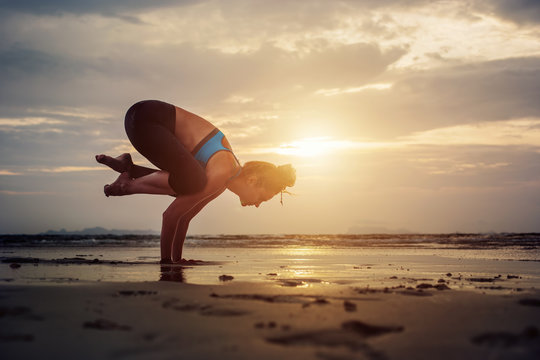 Silhouette of Yoga woman practicing balance yoga asana on sea shore on sunset