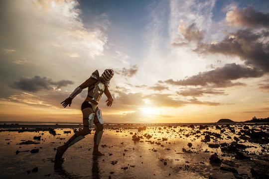 Dancer in fashion robot suit dancing on amazing sunset landscape on sea beach