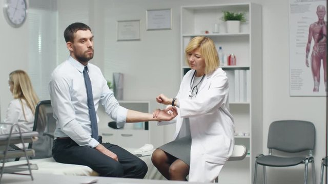 Mid Adult Female Doctor Manually Checks Male Patient's Pulse. Shot on RED Cinema Camera in 4K (UHD).