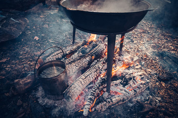 Large pot over a campfire cooking in cast-iron cauldron in natur