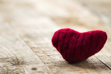 minimalistic close up view of knitted red heart on wooden desk 