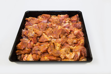 Pieces of pork marinated in spices in a black bowl on a white background