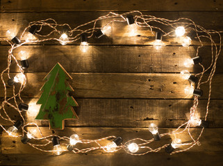 Christmas tree on wood background surround by light bulbs