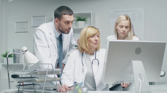 Three Doctors Discuss Medical Issues while Consulting Personal Computer. Shot on RED Cinema Camera in 4K (UHD).