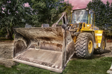 Fototapeta na wymiar Large bulldozer at construction site, sunset in background.