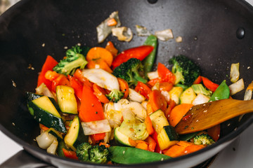Tasty vegetable dish with broccoli and colorful peppers cooked in oil stained asian wok recipe against a white background