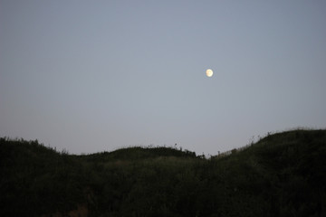Twilight and dusk sky. Dark hills and bright moon on clean sky.