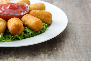 Traditional fried Spanish croquetas (croquettes) with ketchup in plate on wooden background
