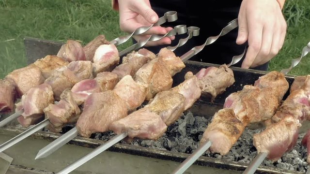 Girl cooks barbeque skewers with meat on hot coal ember brazier Outdoors picnic concept.