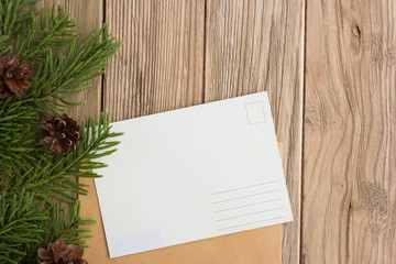 Postcard and christmas tree branch on a wooden table. Cones