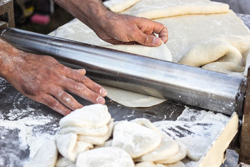 Fototapeta premium Chef making dough pastry sheeter at bakery Baker forming shaping dough rolled pastry metal work table closeup hands process of preparing bread khinkali dough roller machine thin pasta sheet Top view