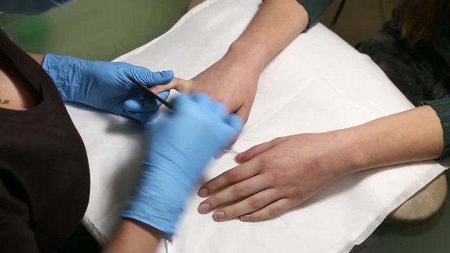 manicurist makes the manicure for young caucasian woman in beauty salon. hands close up