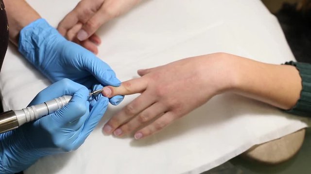manicurist makes the manicure for young caucasian woman in beauty salon. hands close up