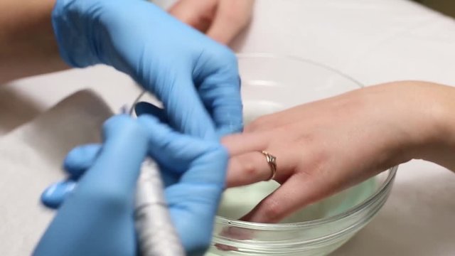 manicurist makes the manicure for young caucasian woman in beauty salon. hands close up
