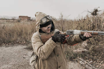 Fototapeta premium wandering boy. young boy aiming a gun. boy shoots. Post apocalypse. Boy traveling on foot in a post-apocalyptic world in search of food. post-apocalyptic world. boy with a gun