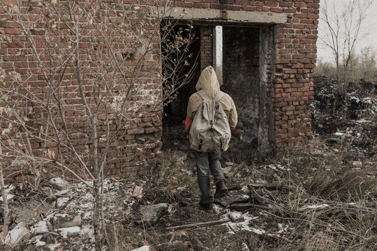 wandering boy. boy goes to an abandoned building. boy stands in front of a building. Post apocalypse. Boy traveling on foot in a post-apocalyptic world in search of food. boy with a gun