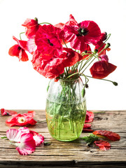 Bouquet of poppy flowers in the vase on the wooden table.