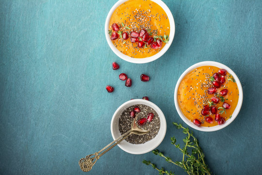Detox orange healthy breakfast smoothies with seasonal ripe fruit, chia seeds, pomegranate  on a bright colored background. Top view. The concept of organic food.