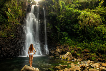 Young woman in bikini standing by Middle Tavoro Waterfalls in Bo