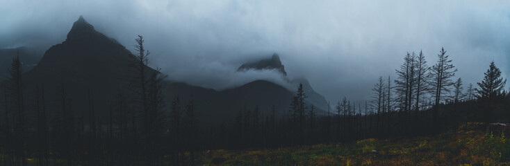 Monochromatic panorama of mountain peaks covered in clouds.