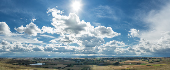 Sun rays in the cloudy sky over fields and villages.