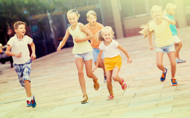 Group of children running together in town on summer