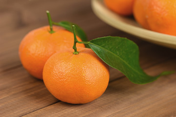 Closeup of ripe mandarin fruit with leaf and group of fruits in background.