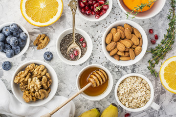 Ingredients for a healthy breakfast, nuts, oatmeal, honey, berries, fruits, blueberry, orange,...