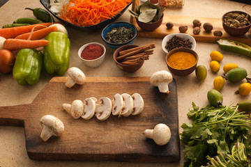 Fototapeta na wymiar Sliced mushrooms on wooden table with vegetables for cooking. He