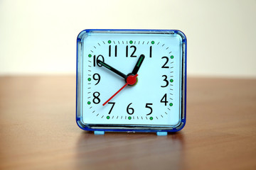 Table clock square shape showing one o'clock on a table front view closeup