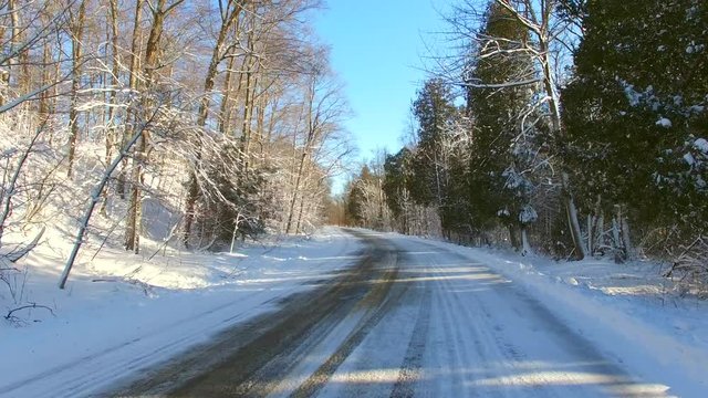 Moving down scenic rural road through snow covered forest in winter. Door County Wisconsin.