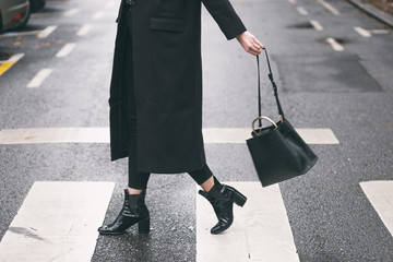 fashion blogger outfit details. fashionable woman wearing a black oversized coat, black jeans,...