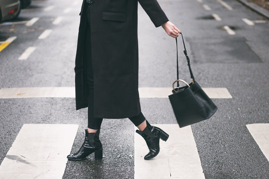 fashion blogger outfit details. fashionable woman wearing a black oversized coat, black jeans, black ankle shoes a black trendy handbag. detail of a perfect fall fashion outfit.

