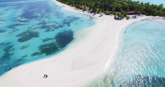Couple on an empty beach. Panoramic landscape seascape aerial view over a Maldives Male Atoll island. White sandy beach seen from above.