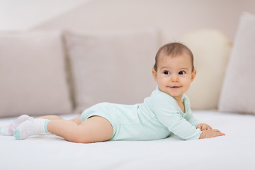 Baby girl on white bed / Cute baby girl lying on her tummy