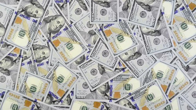Dollar banknotes falling in batches on table covered with cash