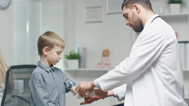 Doctor Takes Off Bandage from Young Boy's Hand. Shot on RED Cinema Camera in 4K (UHD).