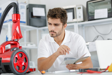 repairman diagnosing vacuum cleaner in his workshop