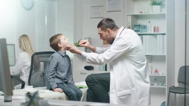 Male Doctor Checks Young Boys Throat. Nurse is Busy in the Background.  Shot on RED Cinema Camera in 4K (UHD).