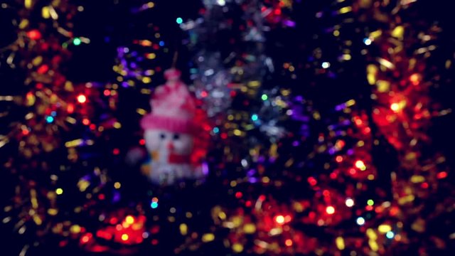 Blurred Christmas flashing lights with tinsel and toy snowman