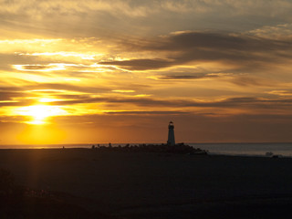 Distant lighthouse backlit by sunrise