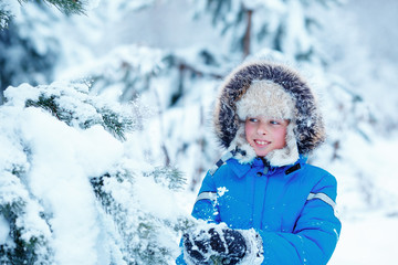 Fototapeta na wymiar Cute little boy wearing warm clothes playing on winter forest