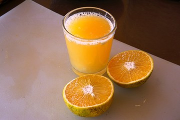 A glass of freshly squeezed tangerine juice with tangerines cut in half