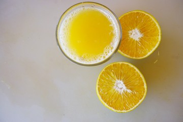 A glass of freshly squeezed tangerine juice with tangerines cut in half
