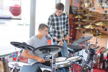 Young men looking at electronic drum kit