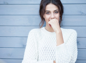 Beautiful natural young smiling shy friendly brunette woman wearing knitted sweater on a grey...